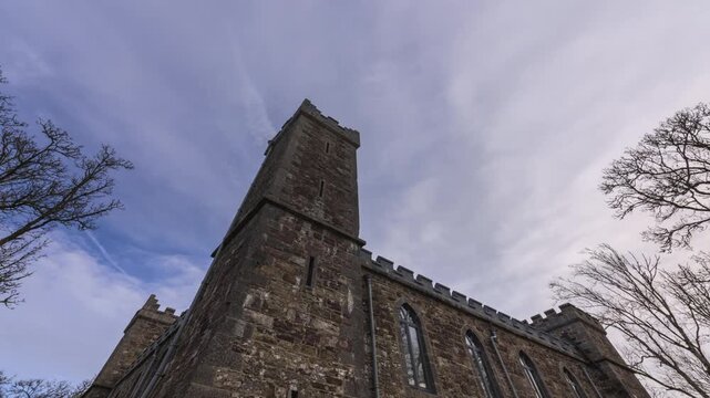 Timelapse of local historical castle surrounded by trees viewed from the ground on early spring sunny cloudy day in county Roscommon in Ireland.