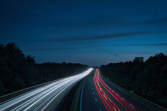 Long exposure of highway traffic at night on the A10 Berlin Ring near Dahlewitz, showing white and red car light trails and overhead road signs towards Dresden and Berlin-Tempelhof