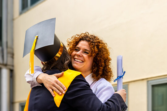 Happy teacher hugging graduating student after university ceremony