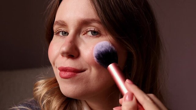 A sequence showing a young woman applying loose powder to her face using a large soft brush, including dipping the brush into the jar and blowing off excess powder