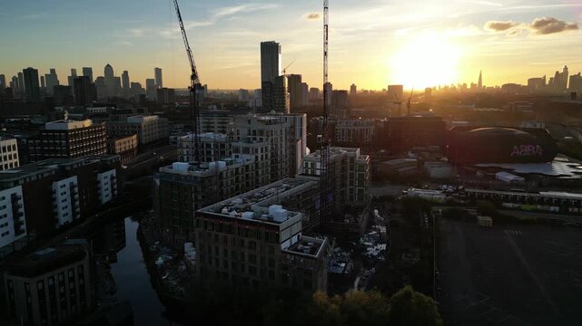 Sun setting over new apartment developments at Pudding Mill Lane and a canal in Stratford, East London, with the Canary Wharf skyline