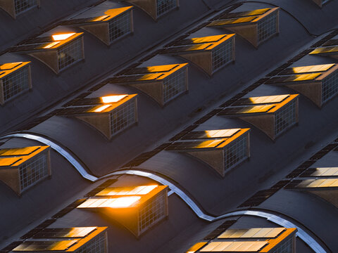 Aerial view of sunlight glints off the tiled roofs and windows, creating a warm glow against the cool shadows, Roma, Lazio, Italy.