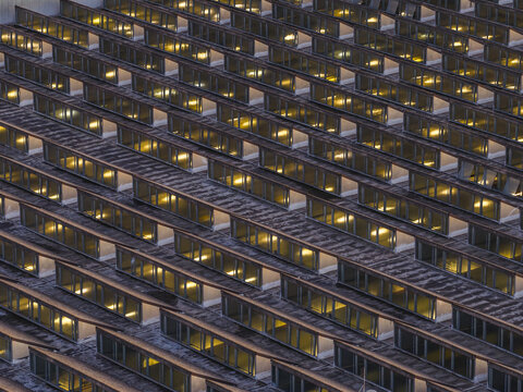 Aerial view of a building with rows of glowing windows creating a warm, inviting pattern against the cool exterior, Roma, Lazio, Italy.