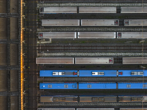Aerial view of train cars painted in shades of grey and blue, lined up on parallel tracks, shimmering in the soft light, Roma, Lazio, Italy.