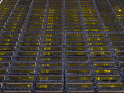 Aerial view of the grid-like facade with windows reflecting golden light, creating a mesmerizing pattern of light and shadow, Roma, Lazio, Italy.