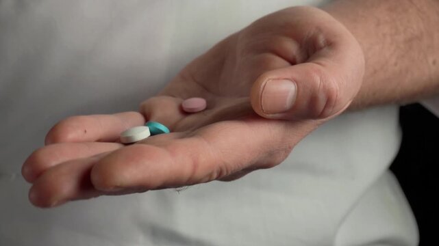 Person adds colorful pills to an open palm, showcasing a gradual increase in quantity and variety of medication in a well-lit indoor setting