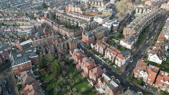 Residents move through West End Lane in West Hampstead, London, showcasing the dense architecture of this affluent transport hub.