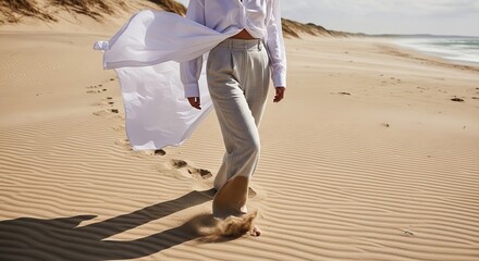 A woman walks alone on a serene beach with flowing white fabric