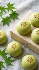 Momiji Manju, Japanese sweets. Green wagashi sweets arranged on fabric with maple leaf motifs and leaves