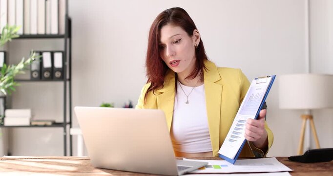 Business woman pointing at a clipboard with financial charts and graphs, effectively communicating business analysis and market trends in an office setting
