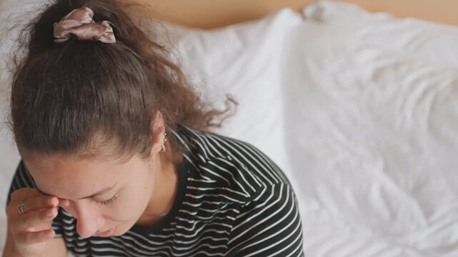 Fatigued sleeper displays silent grief. Sleepwear individual appears weary and mournful silently. An individual in repose demonstrates fatigue coupled with subdued expression of sadness and despair