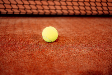 Padel tennis ball resting on clay court