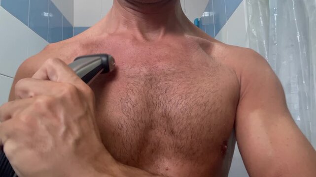 Close-up of an adult man shaving chest hair in a bathroom, highlighting male grooming, body hair removal, personal hygiene, and a daily self-care routine at home