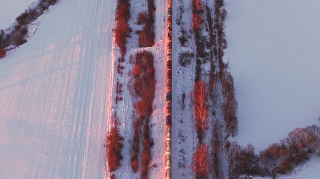 Top down aerial of freight train along snow lined railway