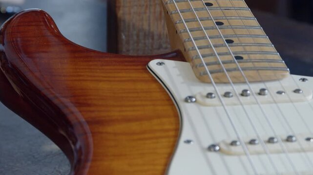 Slow pan from neck fretboard to body of flame maple electric guitar