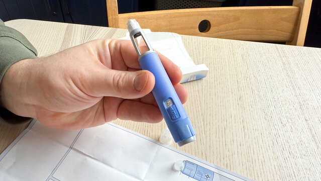 Hand  Ozempic GLP -1  elegantly clasped around a cobalt insulin pen, World Diabetes Day focus, health innovation, subtle empowerment on a serene table