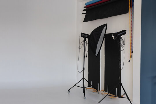 Equipment in a photo studio. Lighting stands with lamps on a white cyclorama background. Copy space.