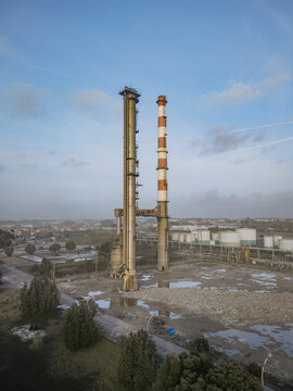 Aerial view of two towering industrial chimneys piercing the skyline, remnants of a bygone era against the muted cityscape, Matosinhos, Porto District, Portugal.