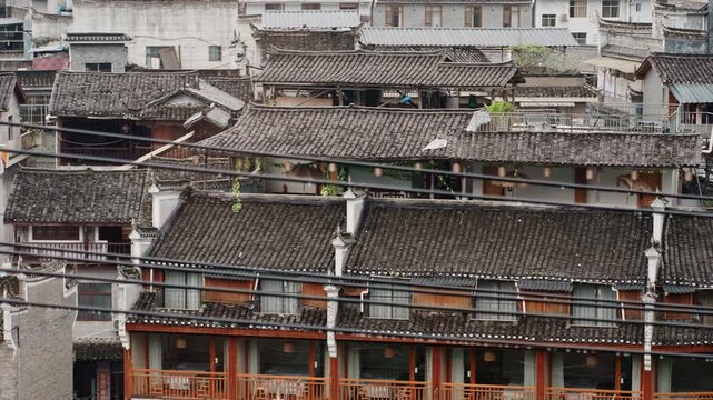Dense hotel row of wooden balconies and tiled roofs, closepacked facades with ornate railings and lanterns, textured weathered surfaces suggest lively streets and longtime commerce