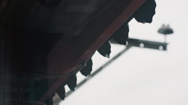 Hotel awning silhouette under overcast sky, ornate eaves and iron bracket with softfocus lamp, muted monochrome palette evoking quiet moody urban exterior closeup perspective highlights texture shadow