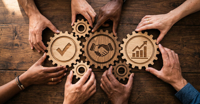 Diverse team working together to align intricately carved wooden gears featuring success, partnership, and growth icons for strategic business integration