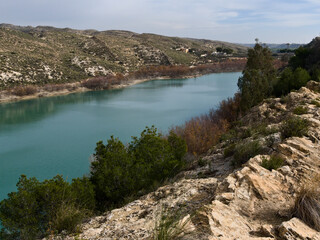 Obraz premium Reservoir lake water reflecting shades of blue and turquoise surrounded by mountains 