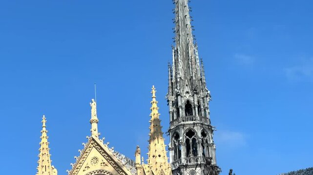 Transept and newly reconstructed 96-meter spire of Notre-Dame Cathedral reaching into a clear blue sky in Paris, France