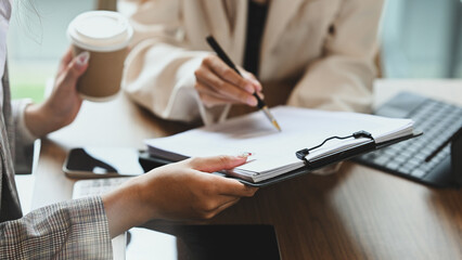 Businesspeople in formalwear reviewing a contract or important paperwork at office