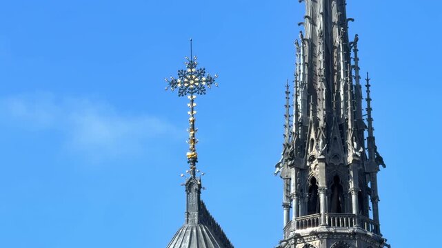 New restored cross at the top of Notre-Dame de Paris cathedral with the spire on the background in France