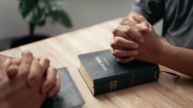 Christian worship and pray. Christian group of people holding hands praying worships together to believe and Bible on wooden table for devotional for prayer meeting concept.