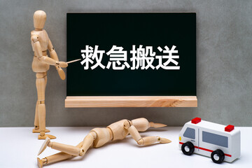 救急搬送で倒れたデッサン人形と救急車と黒板