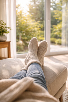 Cozy feet in warm socks relaxing at home in sunlight
