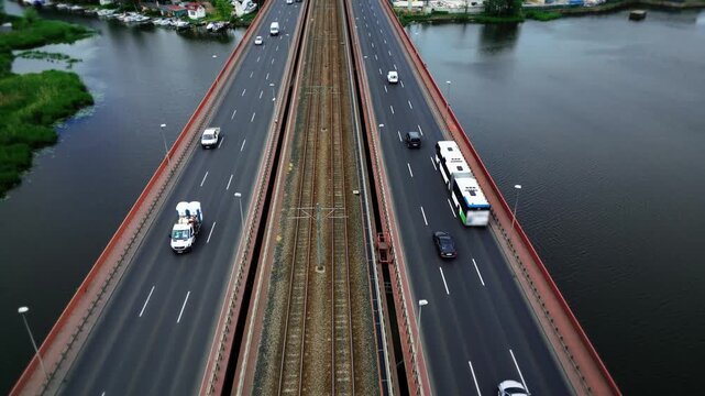 Top-down shooting of the movement of cars, trucks and a passenger bus on the bridge over the river. Aerial view of the urban landscape. 4k footage