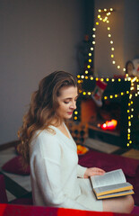 woman sitting and reading a book against the background of the fireplace