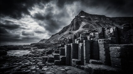 Towering naturally formed geometric basalt columns on a rugged coastal landscape under dramatic skies