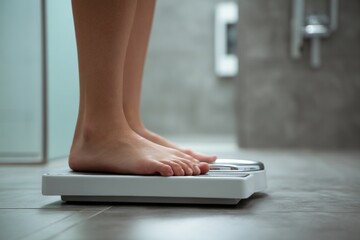 Fototapeta premium Bare feet standing on digital bathroom scale for weight measurement close up