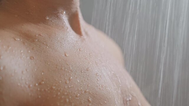 Rejuvenating hotel spa shower chest closeup, water droplets beading on skin, steady rainfall stream, chilled athlete cooling down after workout, warm tile background and minimal boutique suite