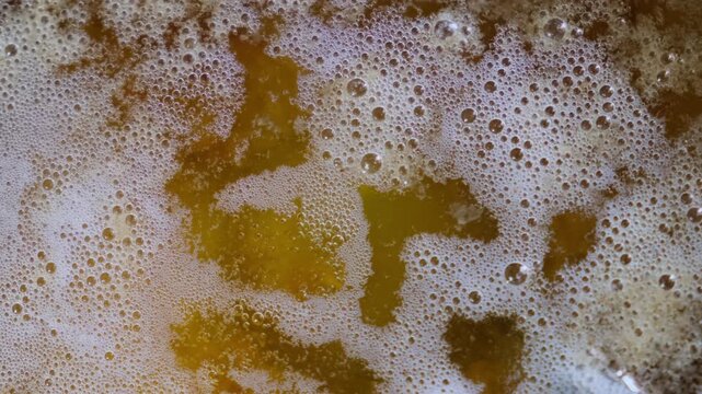 Top view of boiling golden clarified butter or ghee with white froth in a pan