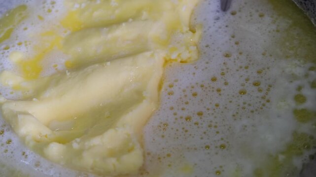 homemade white butter melting in a pan to make traditional clarified butter or ghee