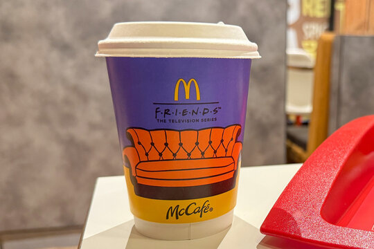 02.03.2026, Batumi, Georgia: Close up of mcdonalds mccafe takeaway coffee cup with friends television series design and iconic orange sofa illustration, 