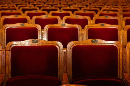 Close-up of Numbered Red Velvet Theater Seats with Wooden Frames