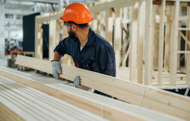 Many of the brand new planks. Male carpenter working with wooden materials in a professional workshop