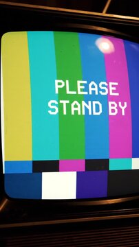 Vintage television screen displaying Please Stand By message with color bars