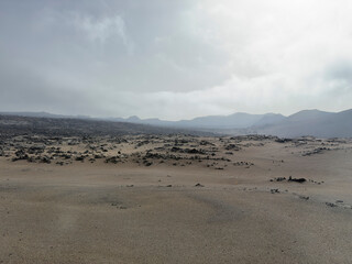 Barren volcanic landscape with rocky terrain and distant mountains.. Volcanic landscape of Timanfaya, Lanzarote, Spain