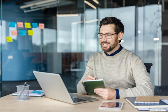 Smiling businessman writing notes during remote online video call