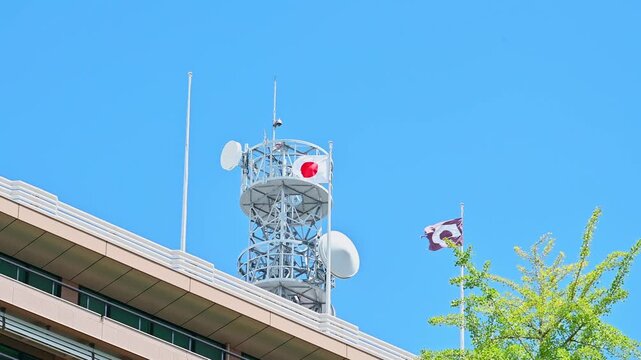  青空に映える電波塔と新緑のイチョウ、はためく国旗
「初夏の爽やかな光を浴びる電波塔。力強くはためく国旗。」
熊本市水前寺(熊本県庁)
A radio tower shining against a blue sky, fresh green ginkgo trees, and a fluttering national flag