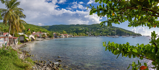 Waterfront of small town Deshaies (Caribbean island Guadeloupe) at sunny afternoon - panoramic view
