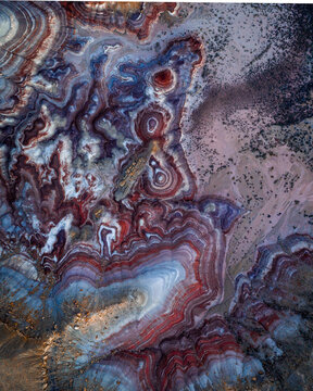 Aerial view of swirling patterns of red, white, blue and grey earth tones creating an otherworldly landscape, Hanksville, Utah, United States.