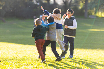 Obraz premium Boys playing with bubbles in a park
