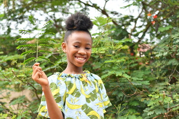 Young African child filled with excitement as she holds a green leaf, healthcare, diet, vitamins, diet, healthy food, greens